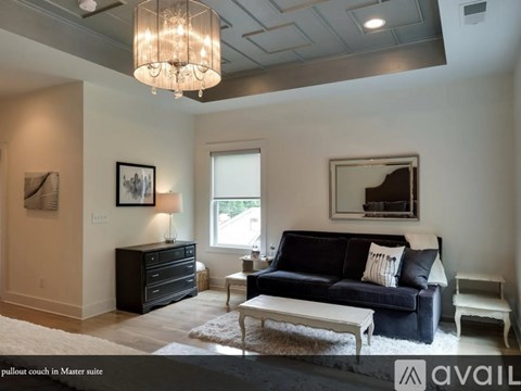 A living room with a black couch and a white coffee table.