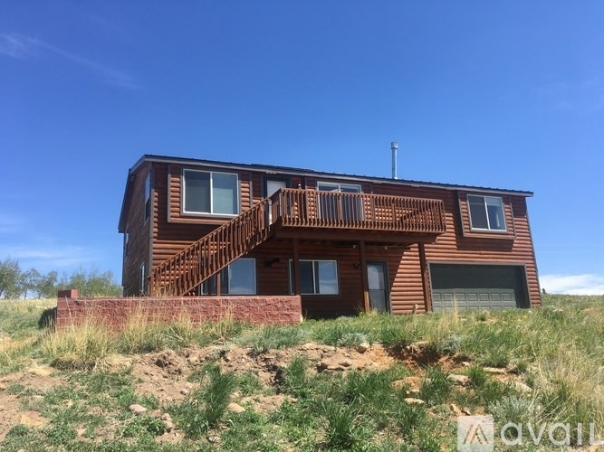 A wooden house with a balcony and a brick wall in the foreground.