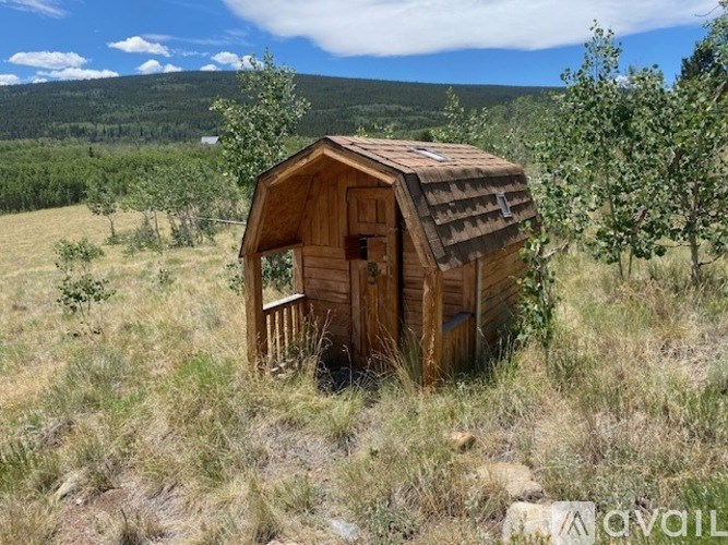 A small wooden hut sits in a field.