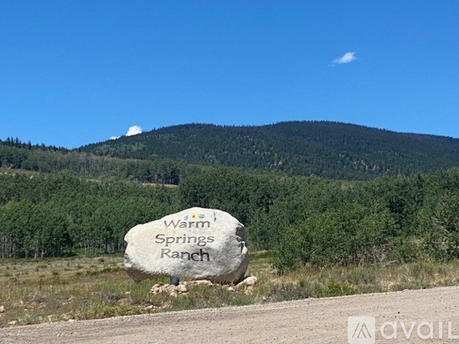 A sign for Warm Springs Ranch is in the foreground with a mountain in the background.