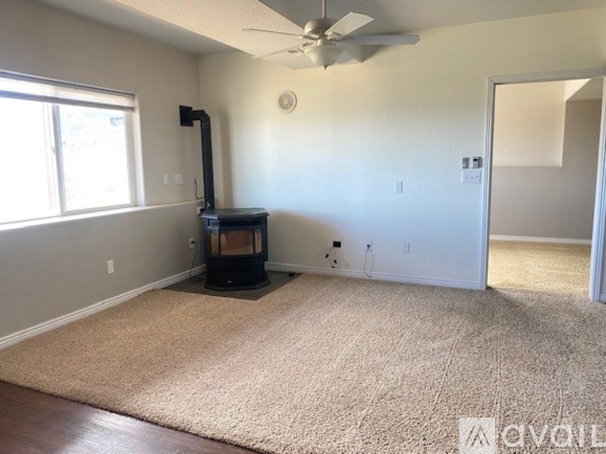 A living room with a fireplace and a fan on the ceiling.