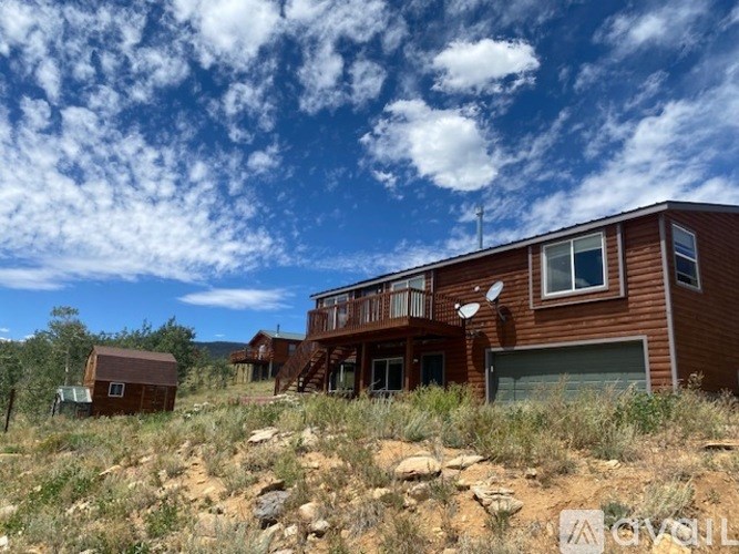 A house with a balcony is surrounded by grass and rocks.