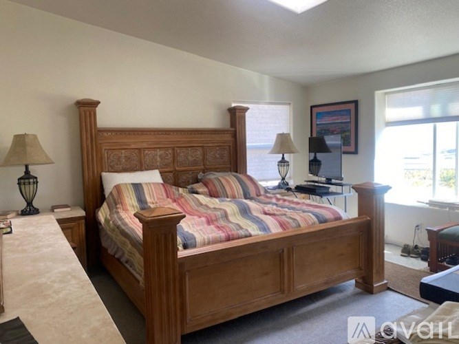 A bedroom with a large bed and two lamps.