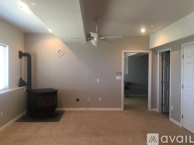 A room with a wood stove and a fan on the ceiling.