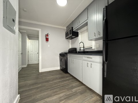 A kitchen with a black refrigerator and white cabinets.