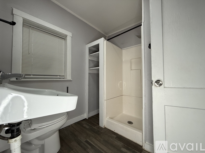 A white sink is in a small bathroom with a white toilet and a walk in shower.