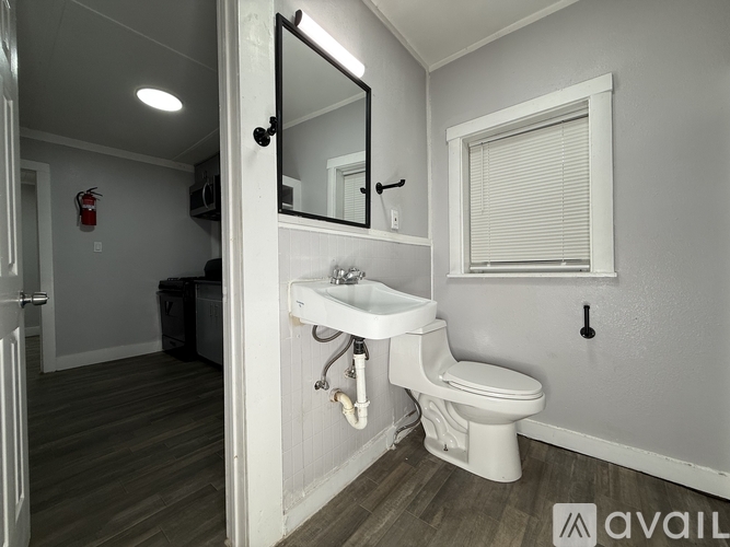 A bathroom with a toilet, sink, and mirror.
