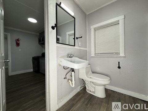 A bathroom with a toilet, sink, and mirror.