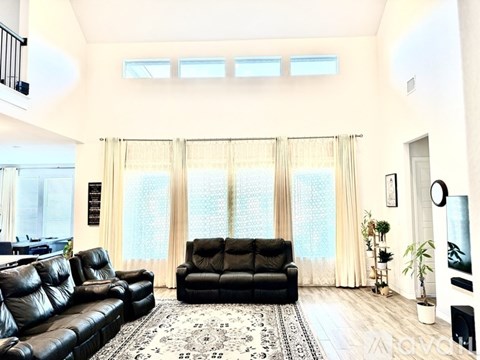 A living room with a black leather couch and a rug.