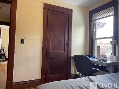 A room with a bed, desk, and chair.