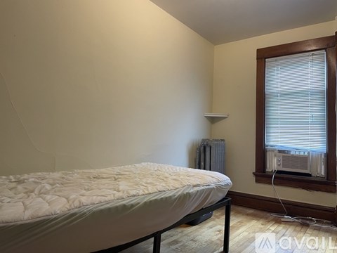 A bedroom with a bed, window, and radiator.