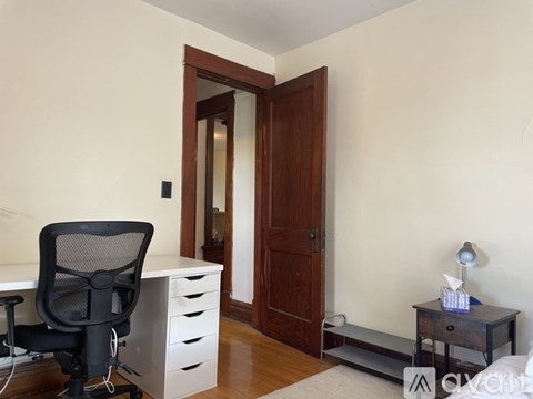 A black chair is in front of a white desk with a computer.