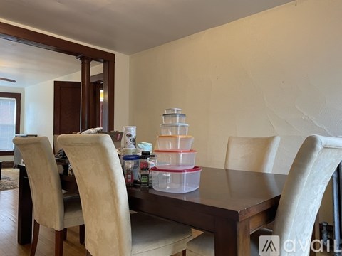 A dining table with four chairs and a stack of containers on it.