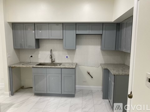 A kitchen with grey cabinets and a granite countertop.