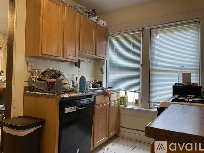 A kitchen with wooden cabinets and a black dishwasher.