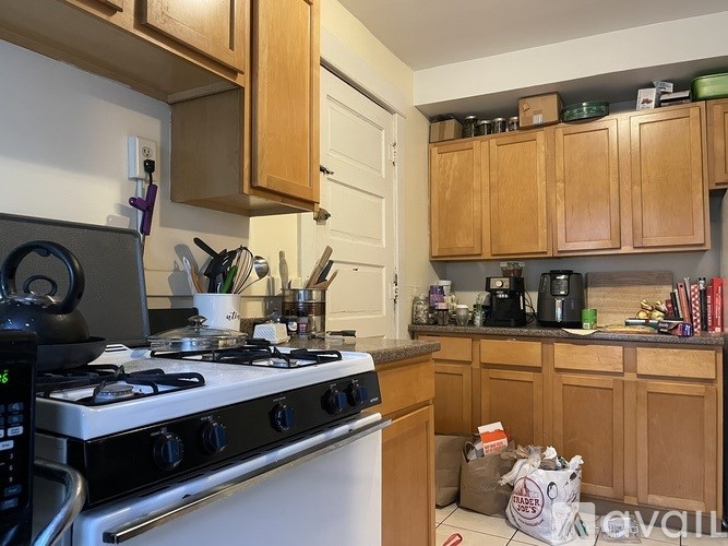 A kitchen with a white stove top and wooden cabinets.