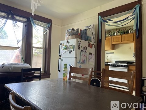A kitchen with a fridge covered in magnets and a table with chairs.