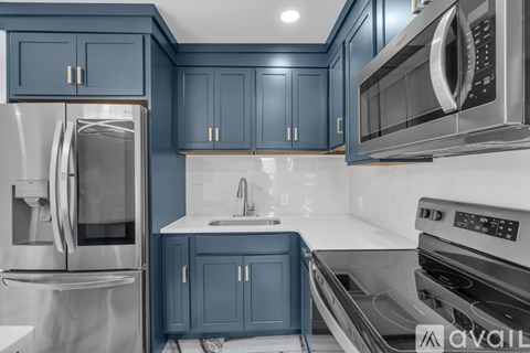A kitchen with blue cabinets and stainless steel appliances.