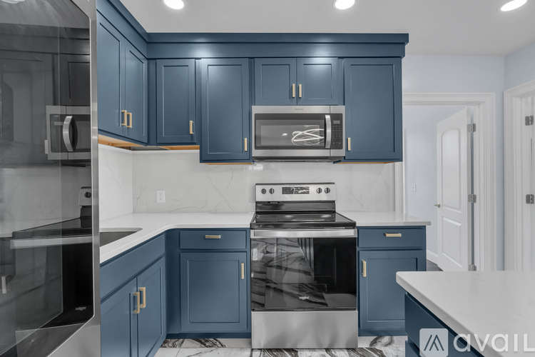A kitchen with blue cabinets and a stainless steel oven.