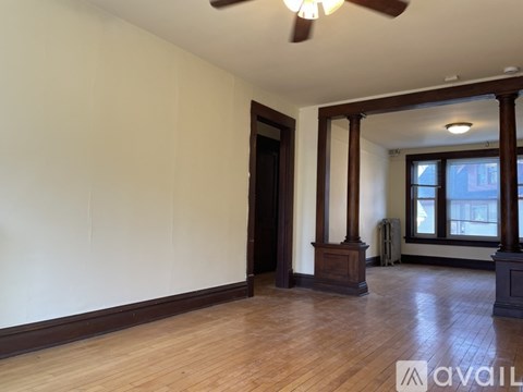 A room with a wooden floor and a white wall with a door and a table with chairs.