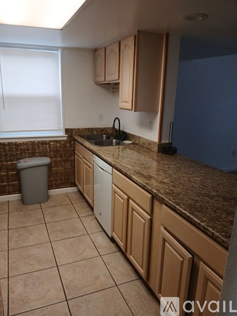 A kitchen with brown cabinets and a brown granite countertop.