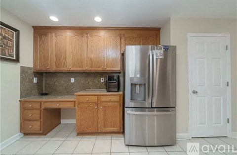 A kitchen with wooden cabinets and a stainless steel refrigerator.