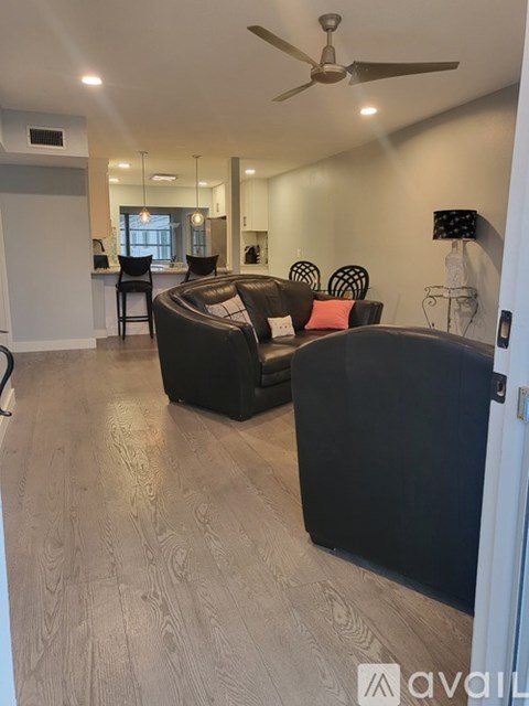 A living room with a black couch and a ceiling fan.