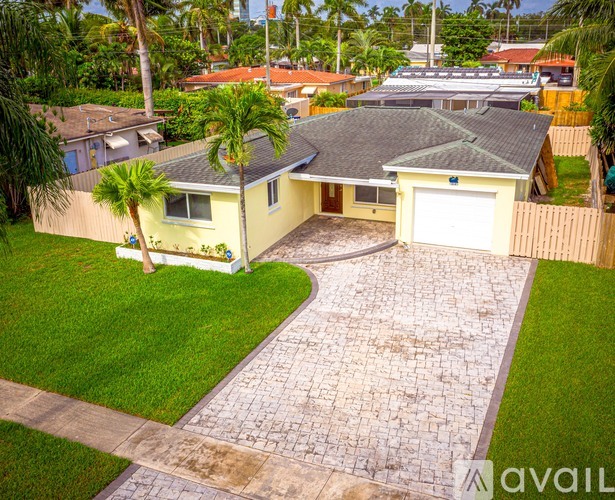 A house with a driveway and a palm tree in front.