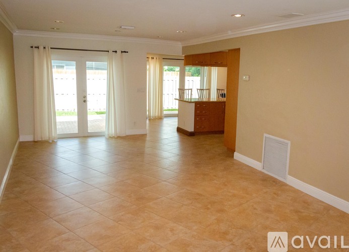 A spacious room with tiled flooring and a large window with curtains.