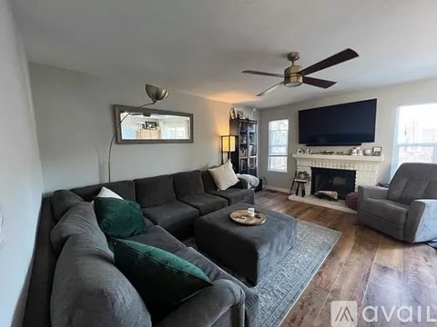 A living room with a grey couch and a fireplace.