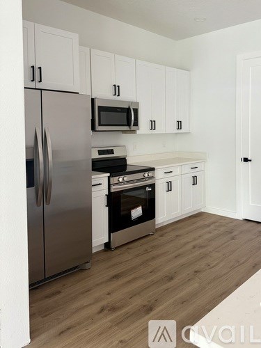 A kitchen with white cabinets and a stainless steel refrigerator.