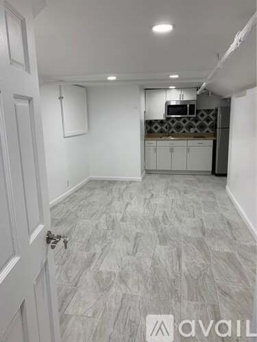 A room with a tiled floor and a kitchen area in the background.
