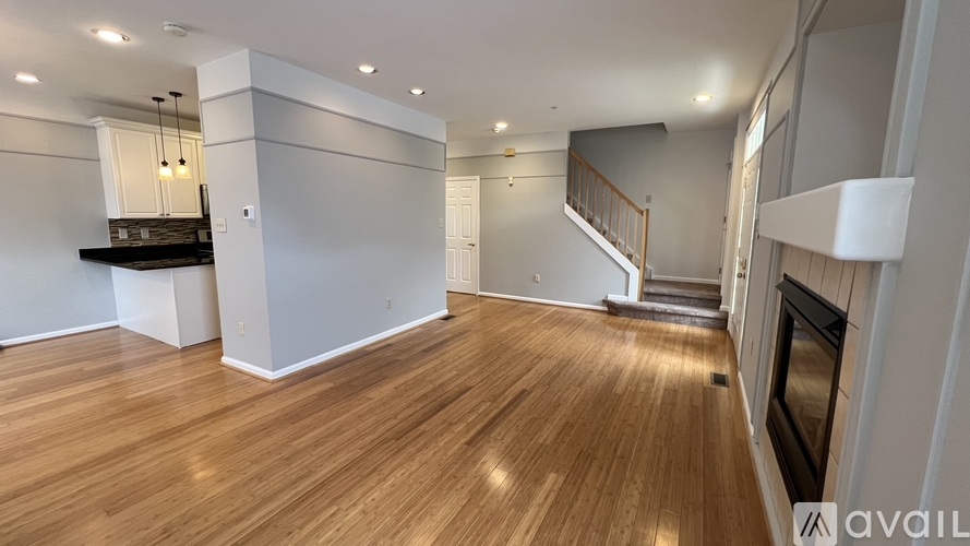 A spacious living room with wooden flooring and a staircase leading to another level.