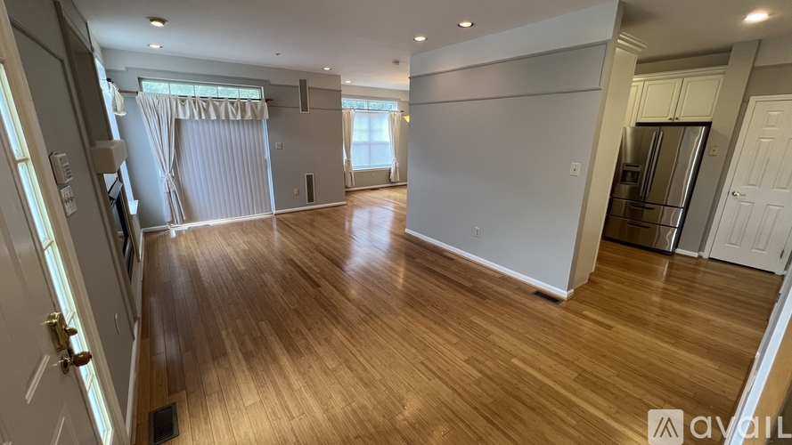 A spacious room with wooden flooring and white walls.