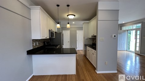 A kitchen with white cabinets and black countertops.