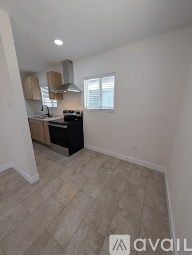 A kitchen with a black stove top oven and a window with blinds.
