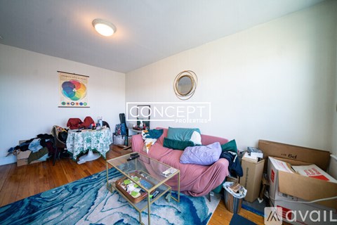 A living room with a glass coffee table and a sofa with a pink throw.