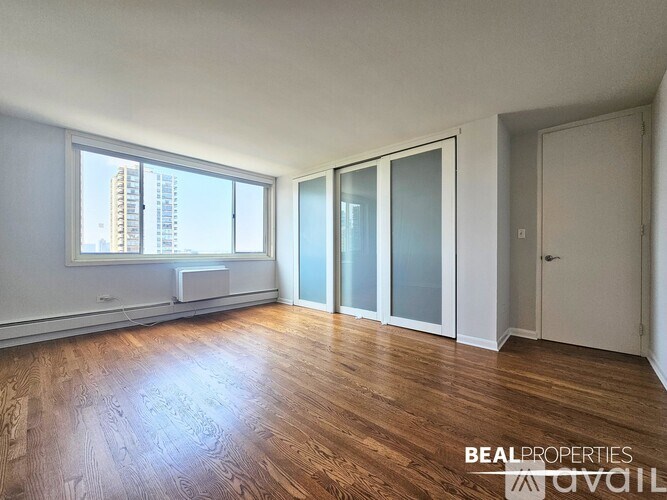 A room with wooden flooring and a large window overlooking a cityscape.