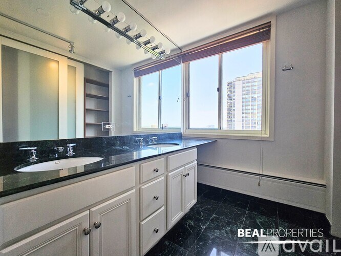 A kitchen with white cabinets and a black countertop.