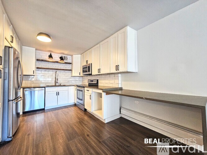 A kitchen with white cabinets and a wooden floor.
