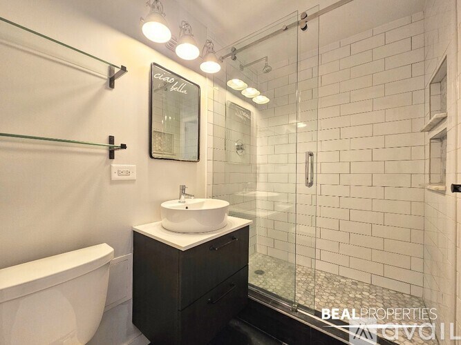 A white sink is on a black cabinet in a white bathroom.