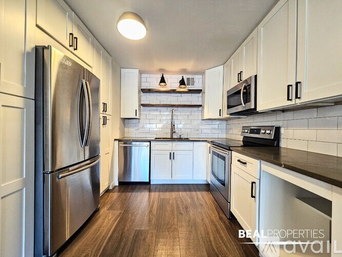 A kitchen with a refrigerator, microwave, oven, and sink.