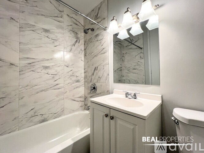 A bathroom with marble tiles and a white tub.