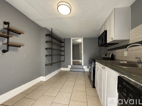 A kitchen with white cabinets and a black microwave.