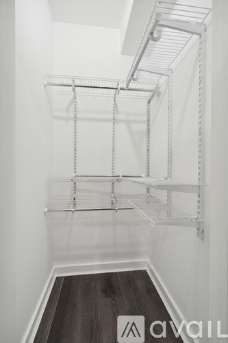 A white walk in closet with shelves and a wooden floor.