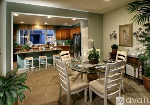 A dining room with a table set for six and a kitchen area in the background.