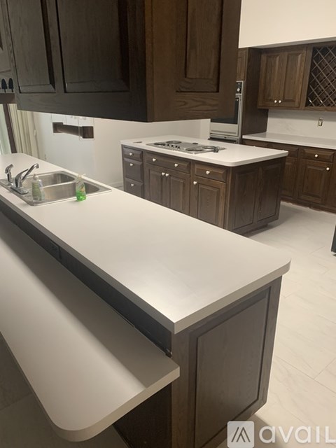 A kitchen with a white countertop and dark brown cabinets.