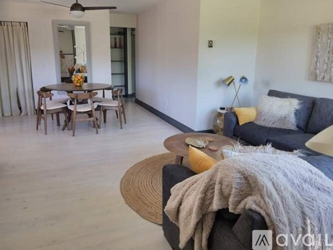 A living room with a grey couch and a wooden dining table.