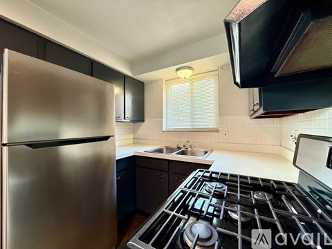 A kitchen with a stainless steel refrigerator and a black stove top.
