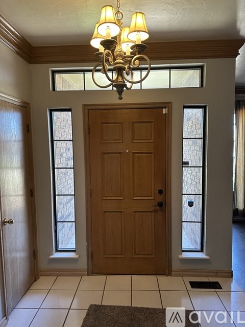 A chandelier hangs over a wooden door in a foyer.